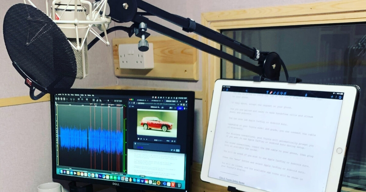 Natalie's booth with a script on the iPad and a recording with soundwaves on the computer screen.