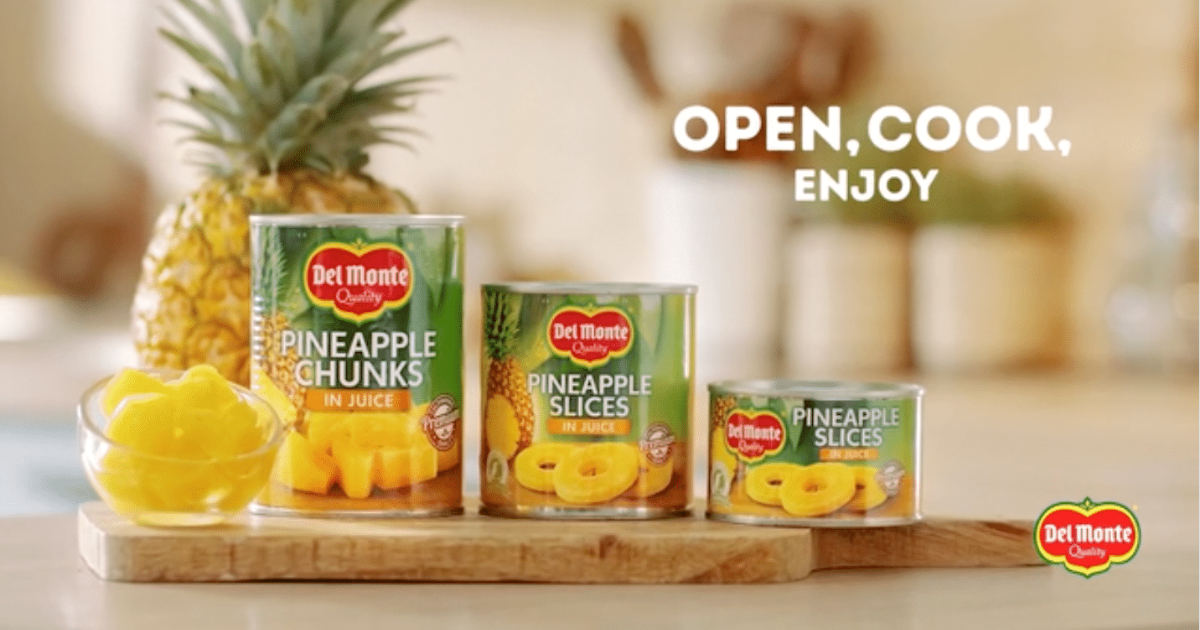 A screenshot from the Del Monte commercial showing three tins of pineapple, a fresh pineapple and the phrase 'open, cook, enjoy'