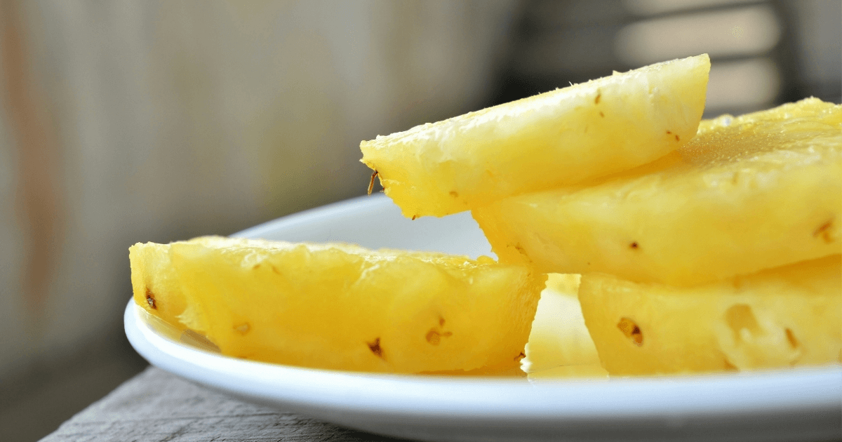 Four slices of pineapple on a white plate.