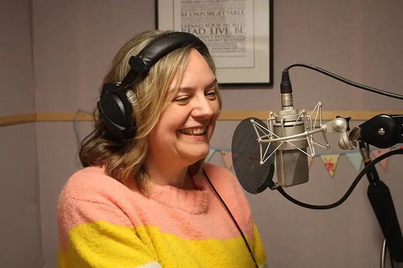 Natalie Cooper in voiceover session, talking into a microphone in a recording studio.