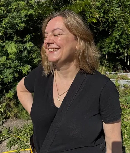 Natalie Cooper standing with her hand on her hip, eyes closed, grinning.