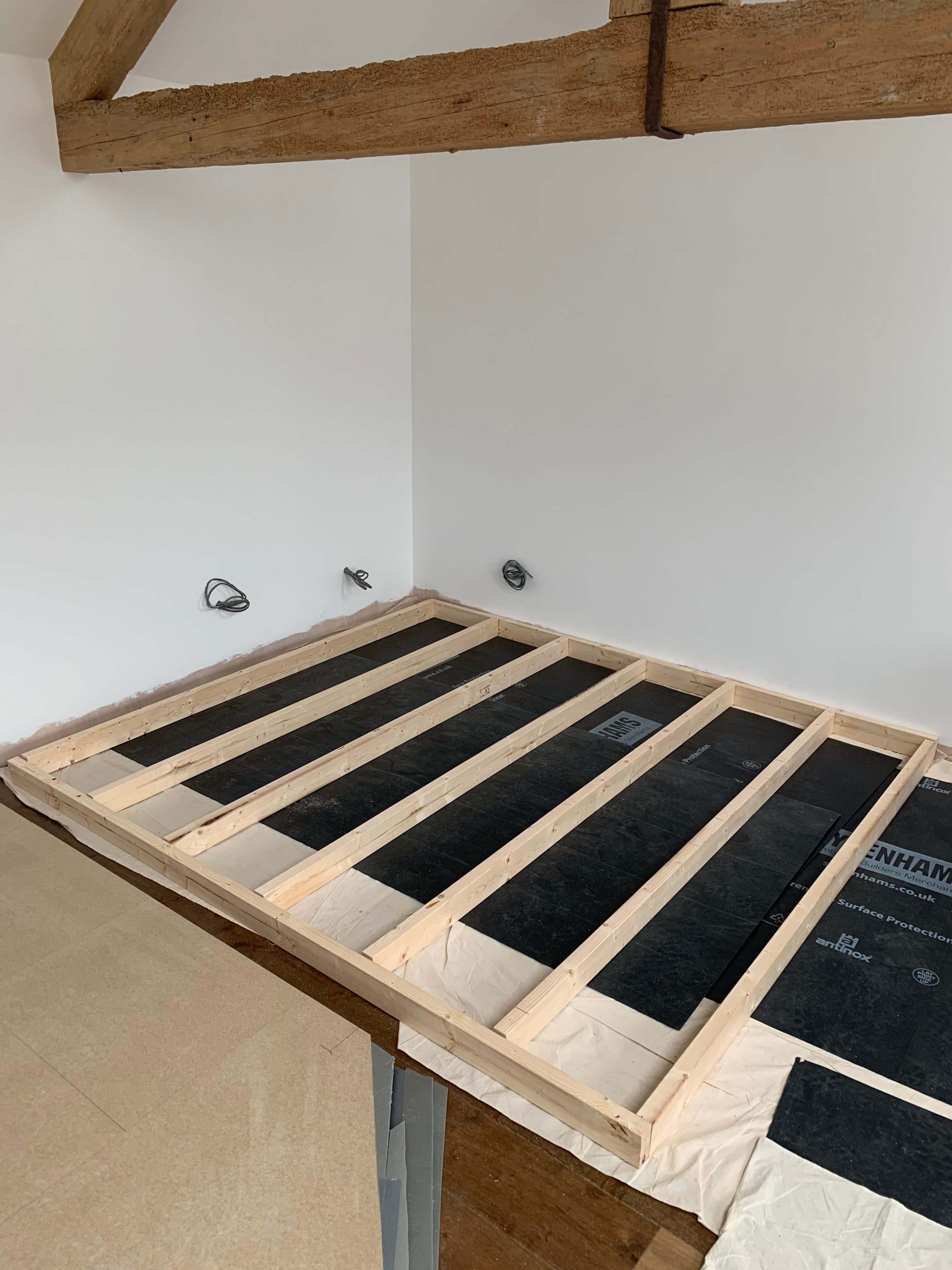 One of the wooden wall structures for a home voiceover recording booth lying on the floor, showing the completed floating floor construction with a layer of TecSound acoustic membrane beneath a chipboard floor layer.